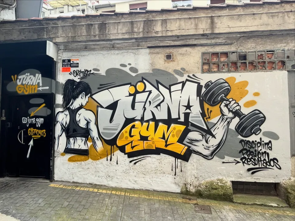 Muro exterior con letras grandes y una figura levantando una mancuerna